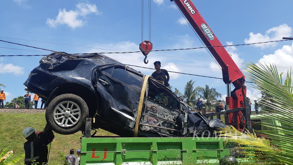 Mobil yang terjepit di jembatan kereta api di Sumpiuh, Banyumas, Jawa Tengah, Rabu (19/4/2023), hancur dan dievakuasi dengan <i>crane</i>.