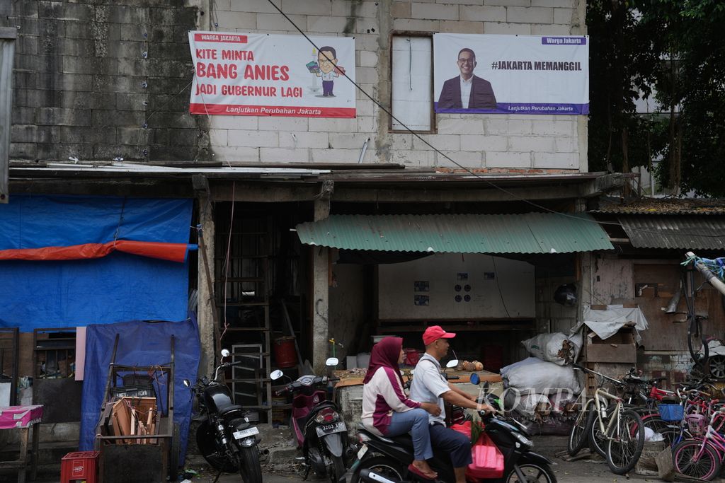 Warga melintasi spanduk bergambar Anies Baswedan di Pasar Manggis, Setiabudi, Jakarta Selatan, Senin (29/7/2024).