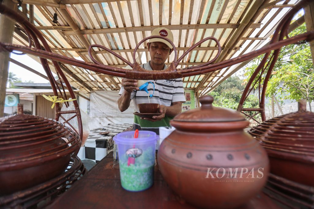 Mustofa (53) melayani pembeli minuman dawet di tempat usaha Dawet Ireng Ketan Hijau Nak Robil miliknya di Desa Pasuruhan, Mertoyudan, Magelang, Jawa Tengah, Selasa (24/10/2023). 