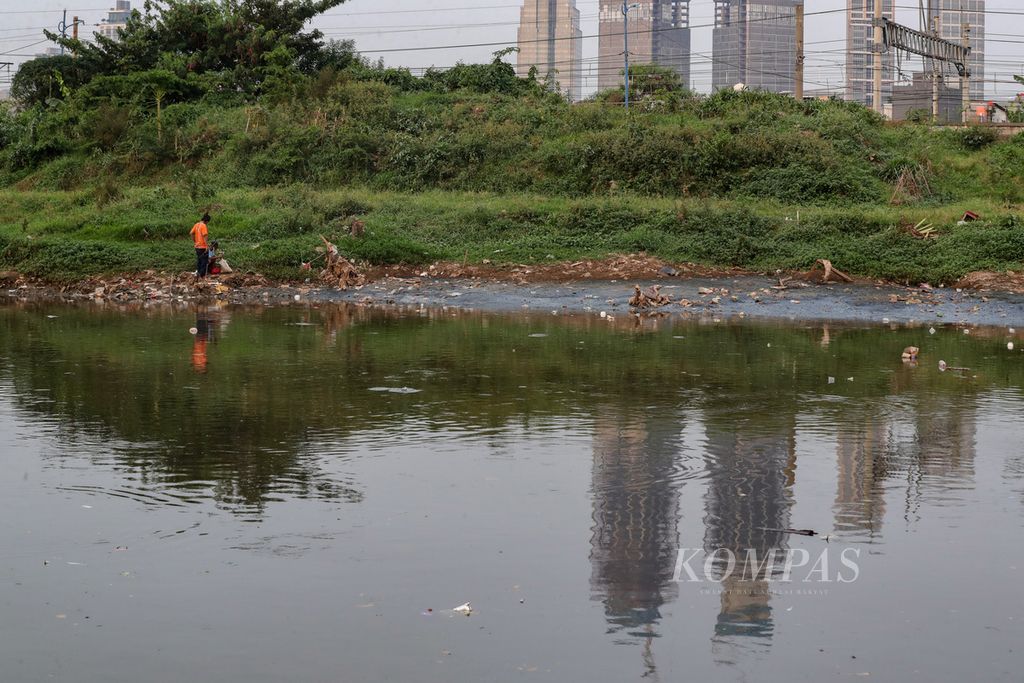 Dua orang warga memancing ikan di Kanal Banjir Barat, Tanah Abang, Jakarta, Rabu (5/7/2023). 