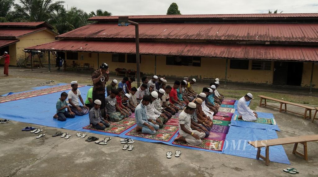 Pengungsi Rohingya melaksanakan shalat Dzuhur berjemaah di lapangan di tempat penampungan pengungsi Rohingya di Yayasan Mina Raya, Kecamatan Padang Tiji, Kabupaten Pidie, Aceh, Kamis (23/11/2023). 