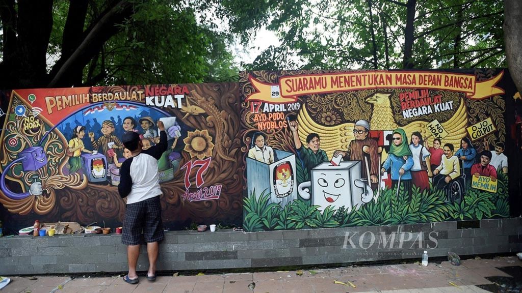 Seniman mural Sugiono menyelesaikan mural bertema partisipasi warga dalam Pemilu 2019 saat mengikuti lomba mural di Jalan Pemuda, Surabaya, Jawa Timur, Rabu (3/4/2019).