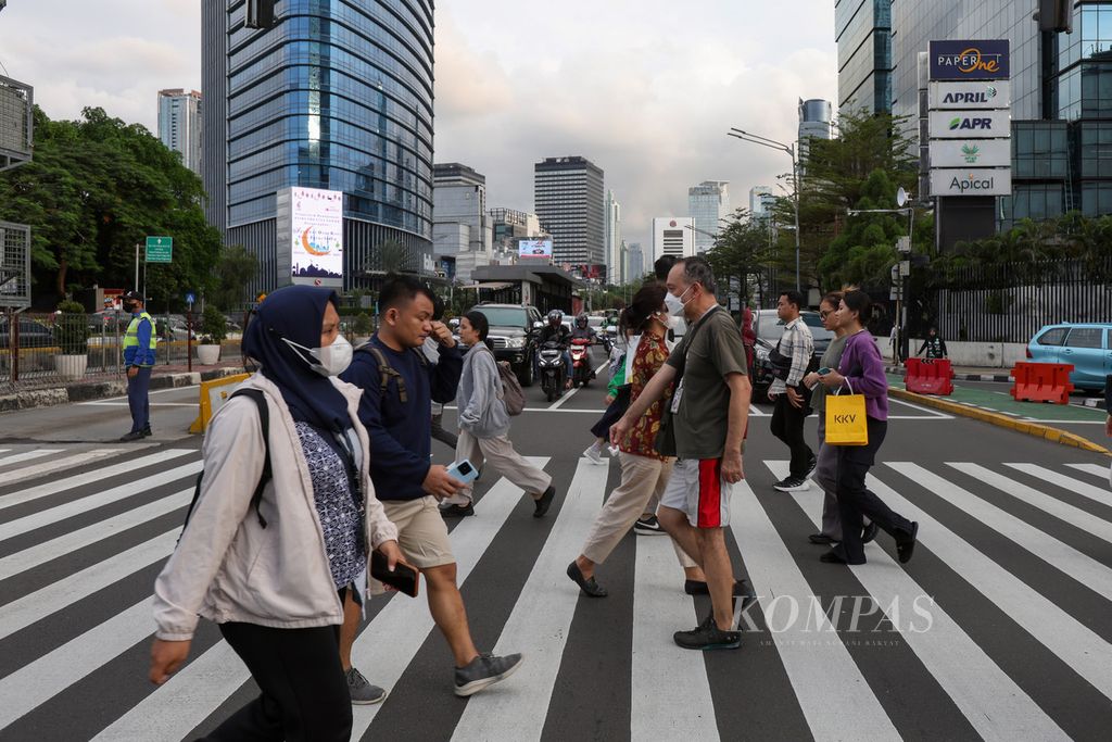 Pedestrians crossing Jenderal Sudirman Street in Jakarta on Tuesday (23/4/2024). The Ministry of Home Affairs assessed that Jakarta will still be a destination for urbanization, even though it will later become the Special Region of Jakarta after the capital city moves to Nusantara Capital.