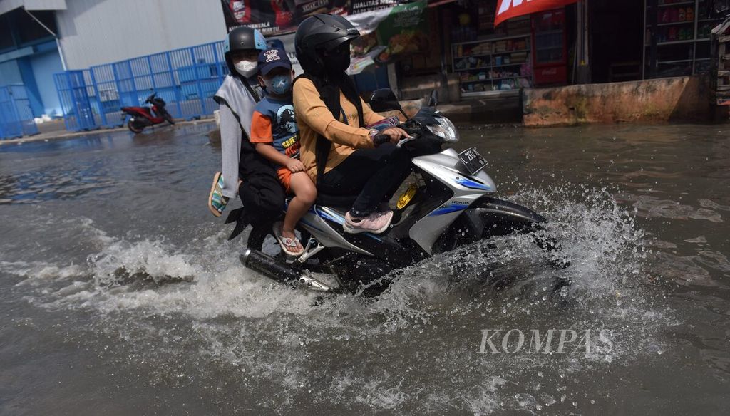 Warga melintasi rob yang melanda jalan menuju Pelabuhan Ujung, Kota Surabaya, Jawa Timur, Senin (16/5/2022). Rob yang melanda kawasan tersebut mencapai ketinggian 60 cm. 