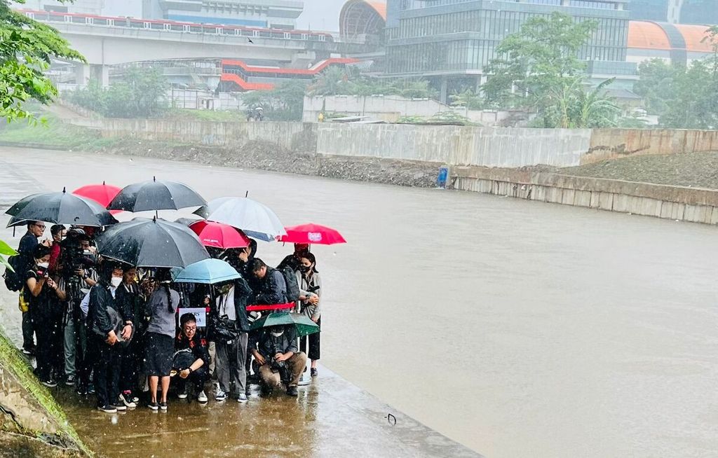 Wartawan meliput Presiden Joko Widodo meninjau Sungai Ciliwung di bawah guyuran hujan, 20 Februari 2023.