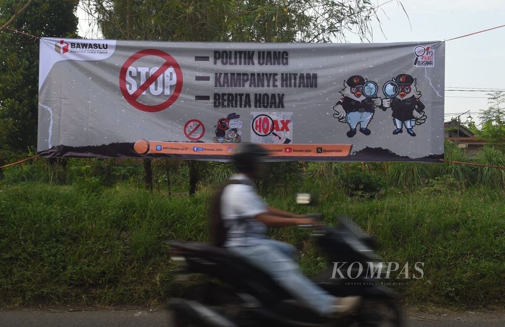 Pengendara melintasi spanduk yang dipasang oleh Bawaslu Jawa Timur di Jalan Raya Sukodono, Sidoarjo, Senin (11/12/2023).