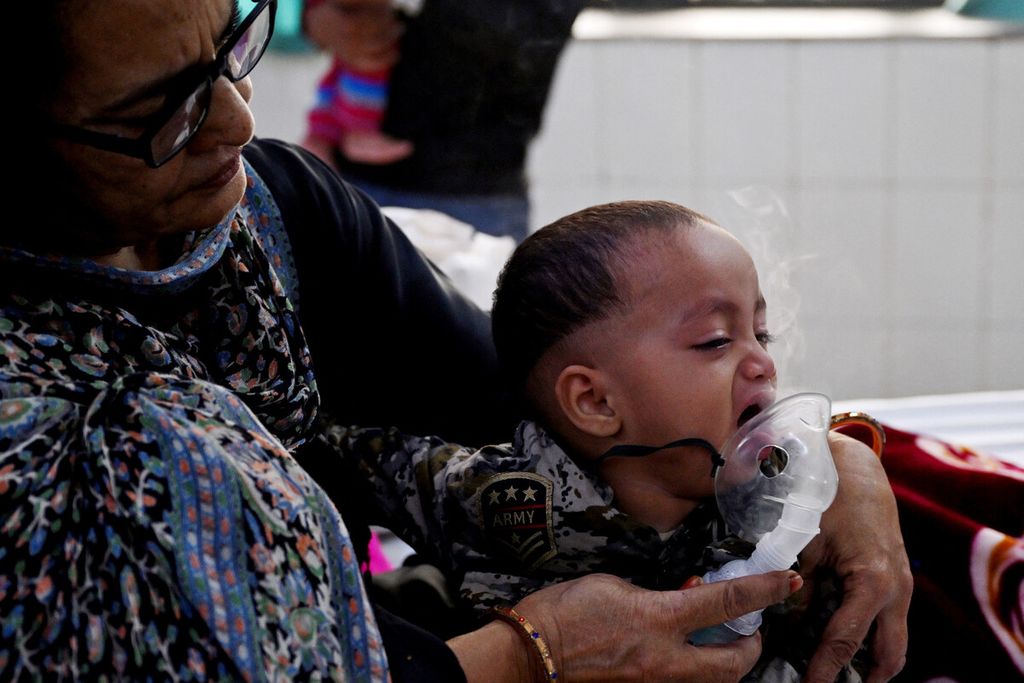 A family member helps a child patient breathe with the help of a nebulizer in the emergency ward of Chacha Nehru Bal Chikitsalaya Children's Hospital in New Delhi, India on Tuesday (11/7/2023). Polluted air has a significant impact on children who have difficulty breathing, with many of them suffering from asthma and pneumonia.