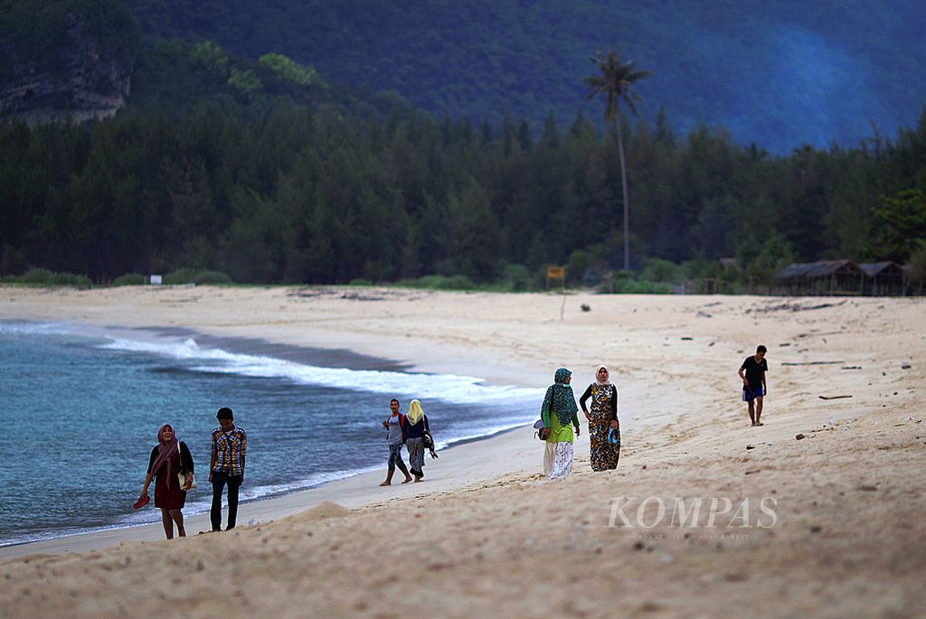 Wisatawan berjalan menikmati pasir putih dan deburan ombak di Pantai Lampuuk, Aceh Besar, Aceh, Rabu (10/12/2014).