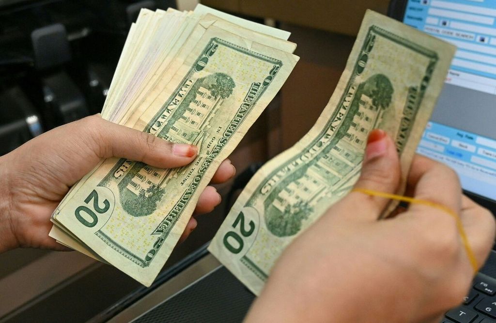 Seorang staf di loket penukaran mata uang asing menghitung uang pecahan dollar AS di pusat kawasan bisnis Raffles Place di Singapura, 6 Oktober 2022. 