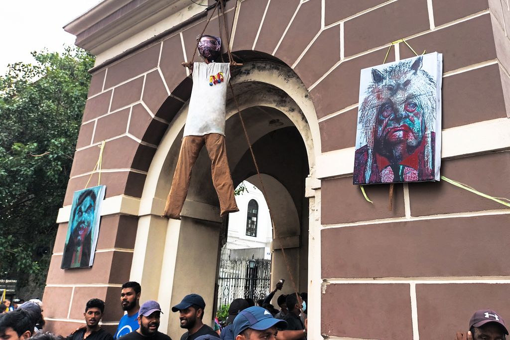 Aktivis berdiri di bawah patung Presiden Sri Lanka Gotabaya Rajapaksa yang tergantung dari menara jam dekat kediaman resminya, di Kolombo, Sri Langka, Minggu (10/7/2022).