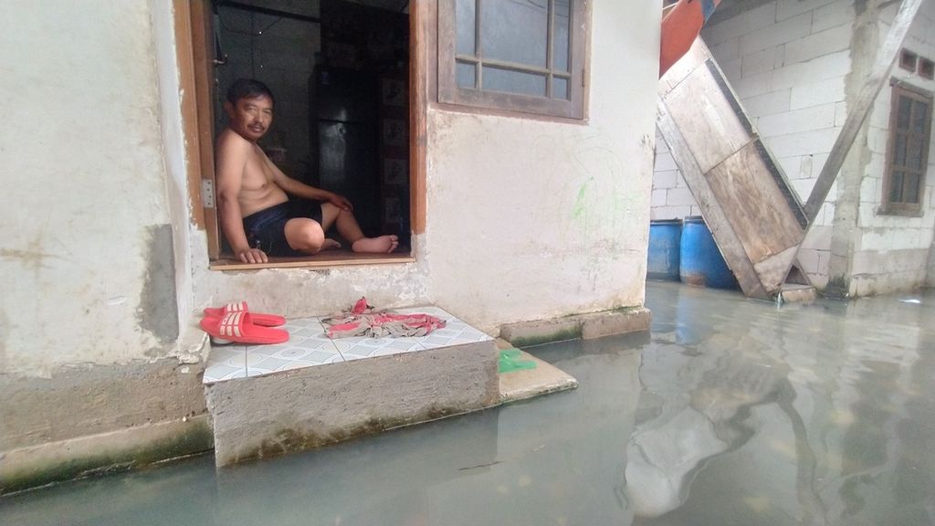 Darjo (62), warga RT 006 RW 022, Kelurahan Pluit, Kecamatan Penjaringan, Jakarta Utara, Senin (26/12/2022), tengah duduk di depan pintu rumahnya. Darjo menceritakan, rob kembali datang pada pagi hari.