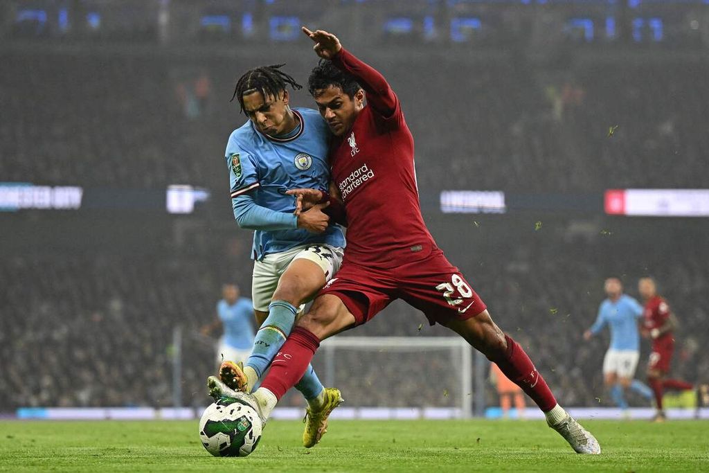 Pemain Manchester City Rico Lewis (kiri) berebut bola dengan pemain Liverpool Fabio Carvalho dalam laga babak 16 besar Piala Liga di Stadion Etihad, Manchester, Inggris, Kamis (22/12/2022). City menang 3-2 pada laga itu. 