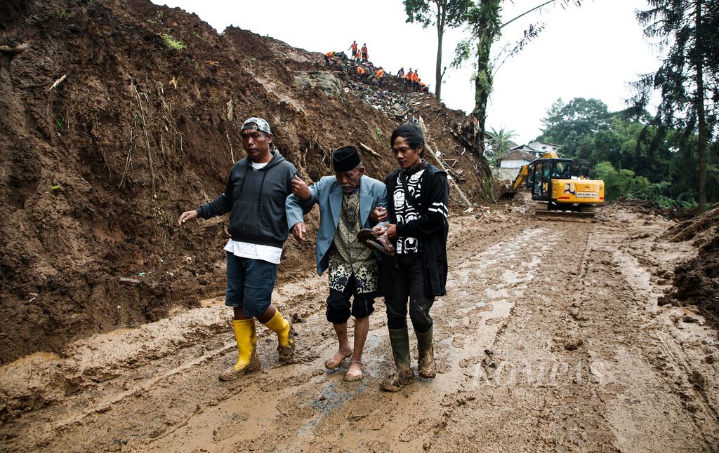 Two men helped their sick elderly relative cross the Mangunkerta road which was previously closed by a landslide in Cijedil Village, Cugenang District, Cianjur Regency, West Java, Saturday (26/11/2022).