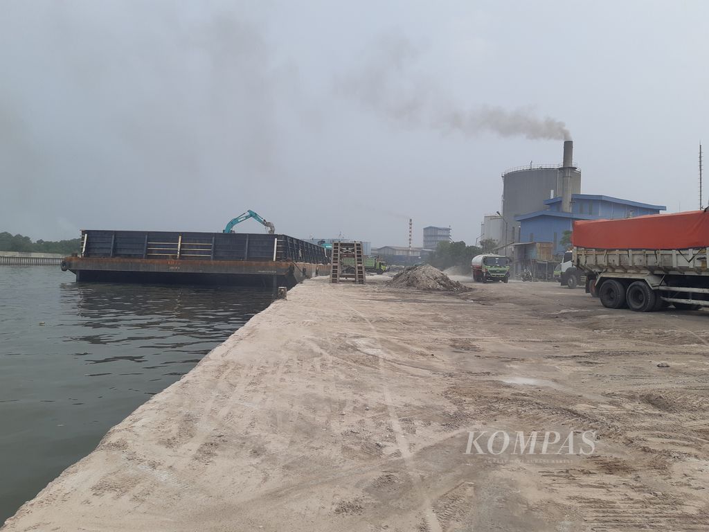 Aktivitas bongkar muat di Pelabuhan Marunda, Jakarta Utara, pada Jumat (1/4/2022) sore. Asap tampak membubung tinggi dari salah satu pabrik yang beroperasi di dalam Kawasan Berikat Nusantara.