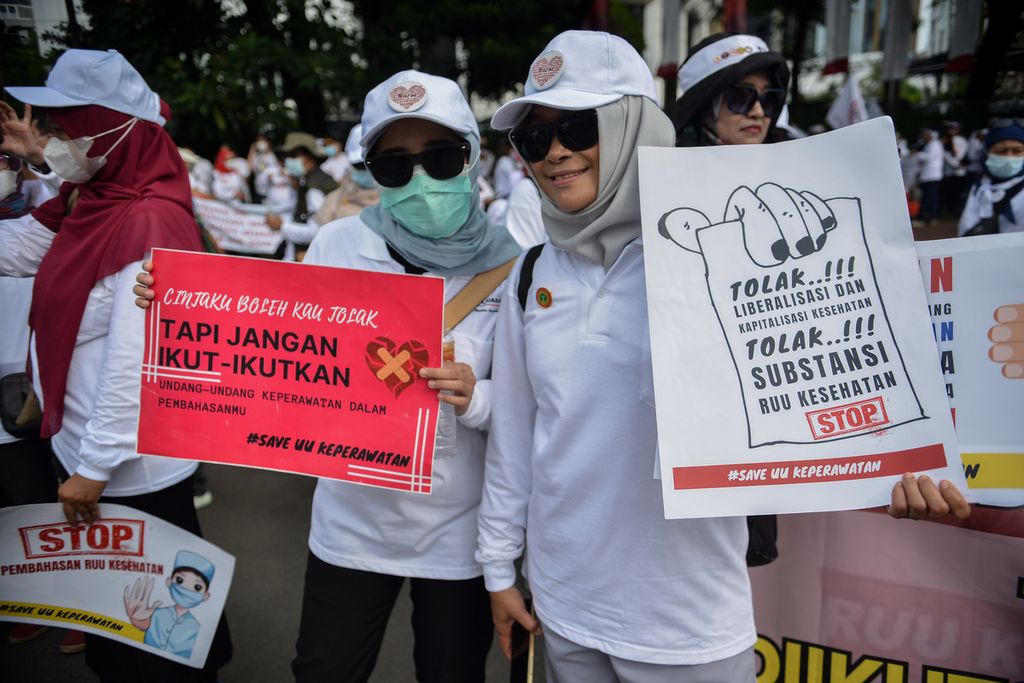 Dua peserta aksi mengangkat poster berisi pesan penolakan Rancangan Undang-Undang Omnibus Law Kesehatan saat aksi di kawasan Patung Kuda Arjuna Wiwaha, Jakarta Pusat, Senin (8/5/2023). 