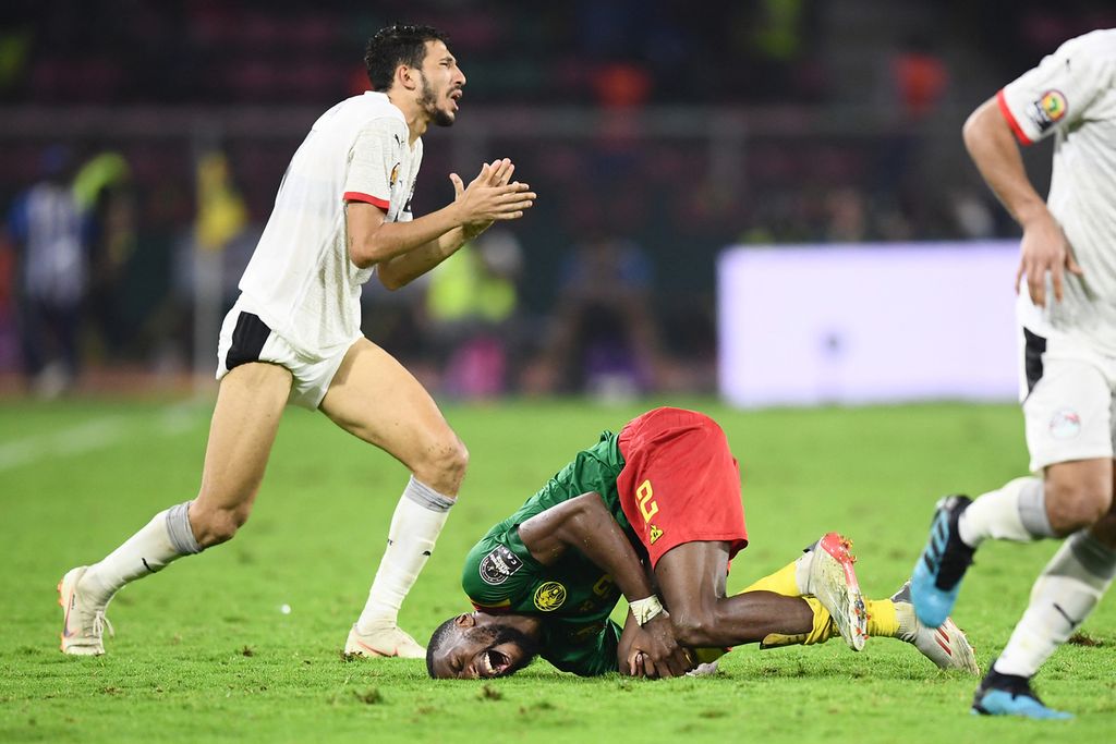 Penyerang Kamaerun, Karl Toko Ekambi (tengah), mengerang kesakitan seusai dilanggar bek Mesir, Ahmed Abou el Fotouh (kiri), pada babak semifinal Piala Afrika 2021 di Stadion Olembe di Yaounde, Kamerun, Jumat (4/2/2022) dini hari WIB.