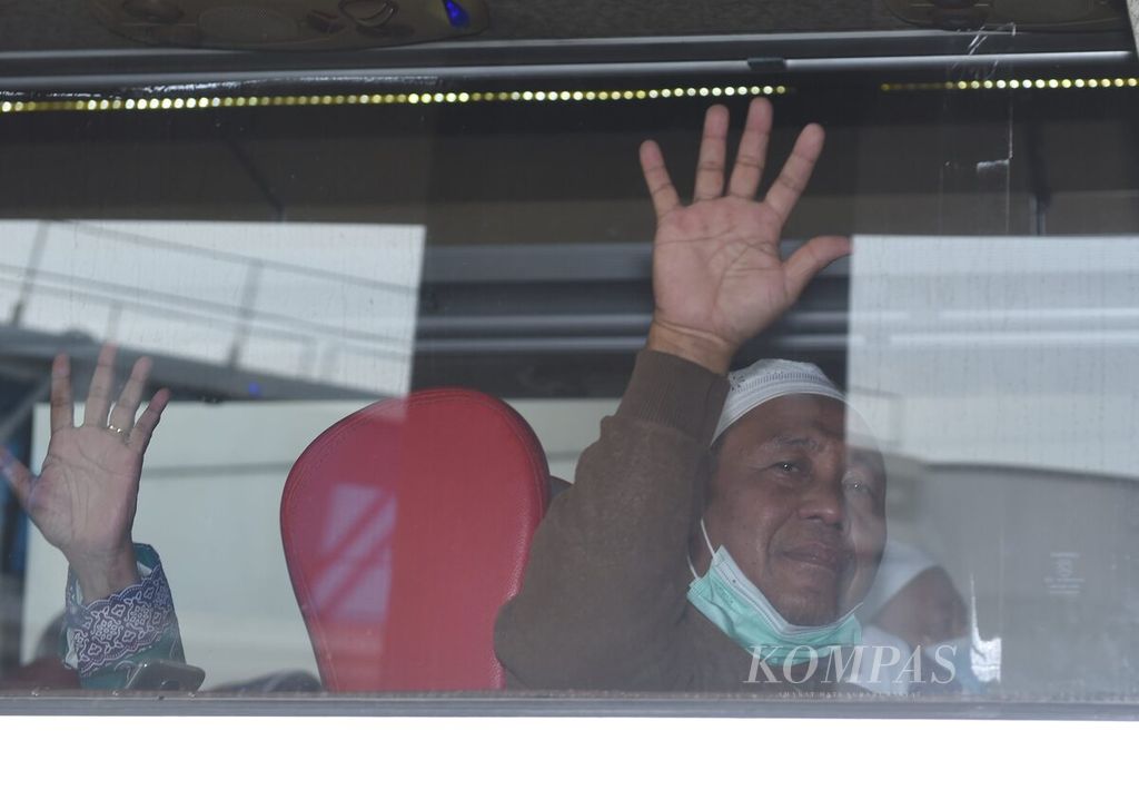 Jemaah haji Kloter 1 Debarkasi Surabaya yang baru turun dari pesawat Saudi Arabia Airlines melambaikan tangan dari dalam bus di Terminal 2 Bandara Internasional Juanda Surabaya di Kabupaten Sidoarjo, Jawa Timur, Minggu (17/7/2022).