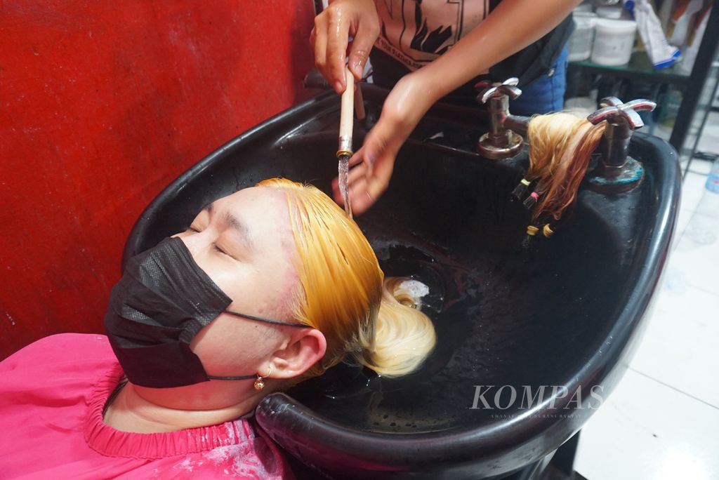 Penata rambut mencuci rambut Leidy Lala (36) dalam proses pengecatan di El Beauty Salon, Ranotana, Manado, Sulawesi Utara, Minggu (19/12/2021). Permintaan pengecatan rambut sedang meningkat di Manado menjelang Natal dan Tahun Baru.