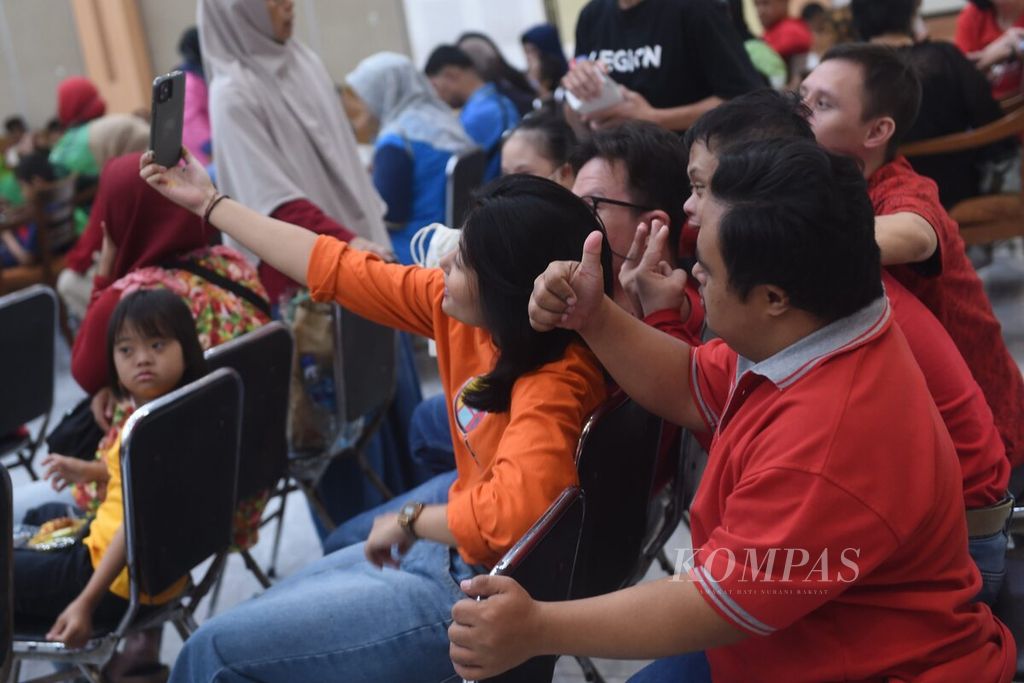 Participants take photos after drawing together with students with intellectual disabilities and Down syndrome at the East Java Social Welfare Activities Coordinating Agency Building in Surabaya, Thursday (2/5/2024).