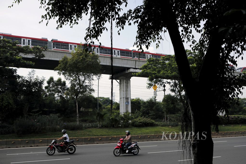 Pengendara melintas di sekitar jalur kereta ringan (LRT) Jabodebek di Jalan Mayjen Sutoyo, Jakarta Timur, Minggu (13/6/2021).