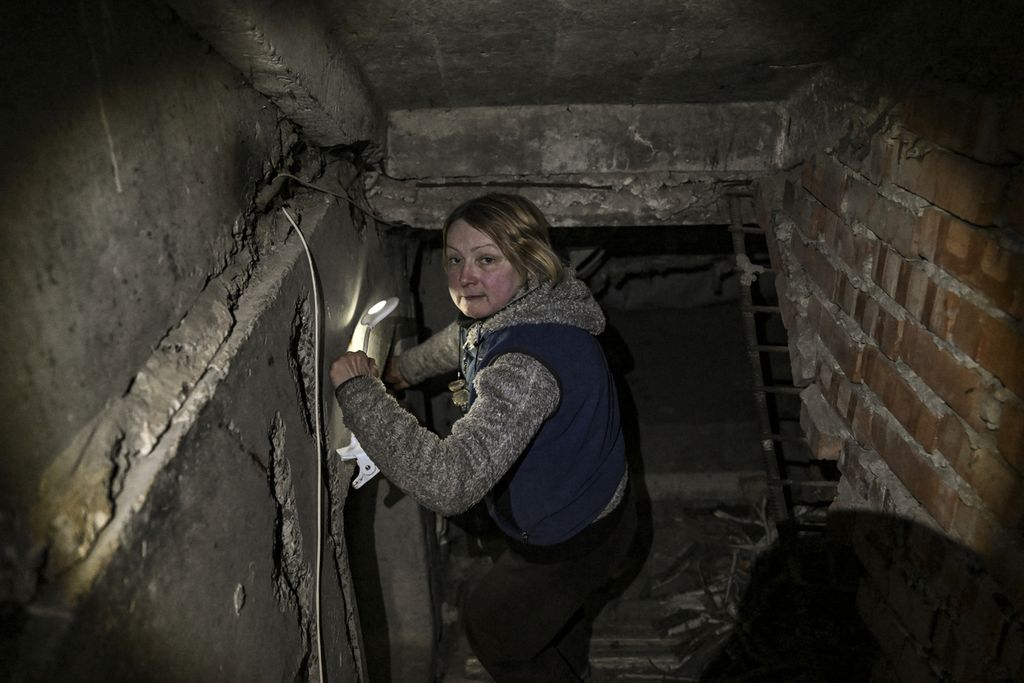 Seorang perempuan menoleh saat hendak masuk ke ruang perlindungan bawah tanah di Chasiv Yar, dekat kota Bakhmut, Ukraina timur, 5 Maret 2023, di tengah serangan pasukan Rusia. 