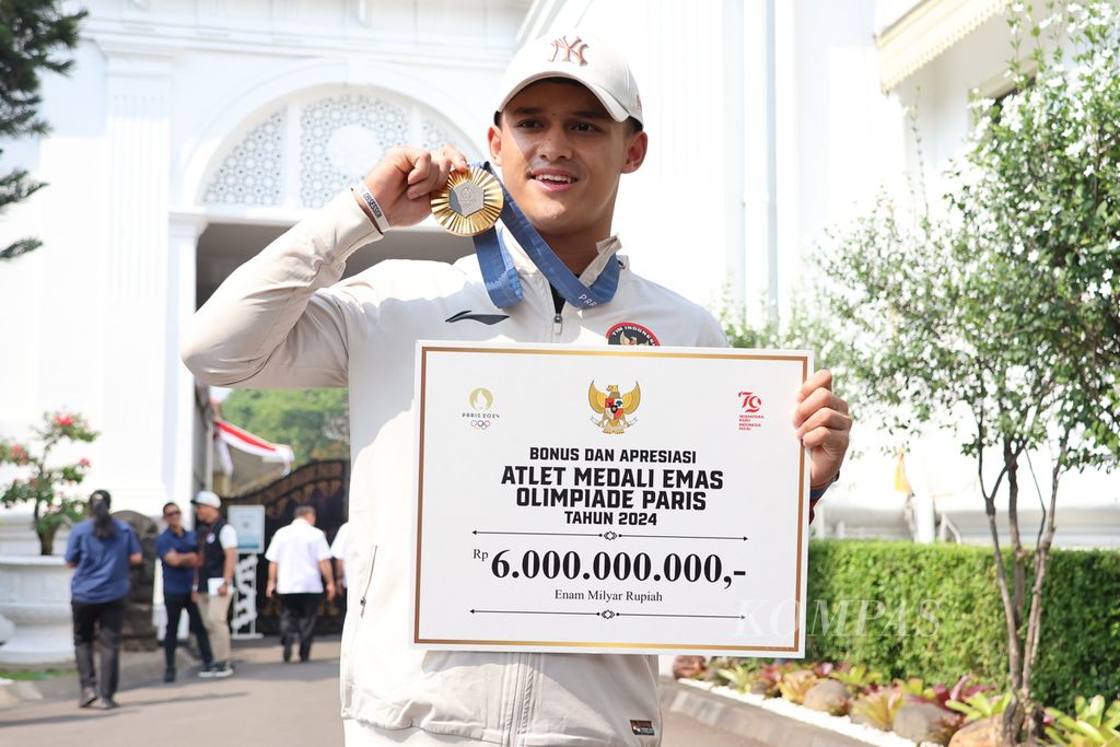 Atlet angkat besi 73 kg Rizki Juniansyah menunjukkan medali emas Olimpiade Paris 2024 yang diraihnya. Rizki bersama para atlet dan pelatih bertemu Presiden Joko Widodo, Kamis (15/8/2024).