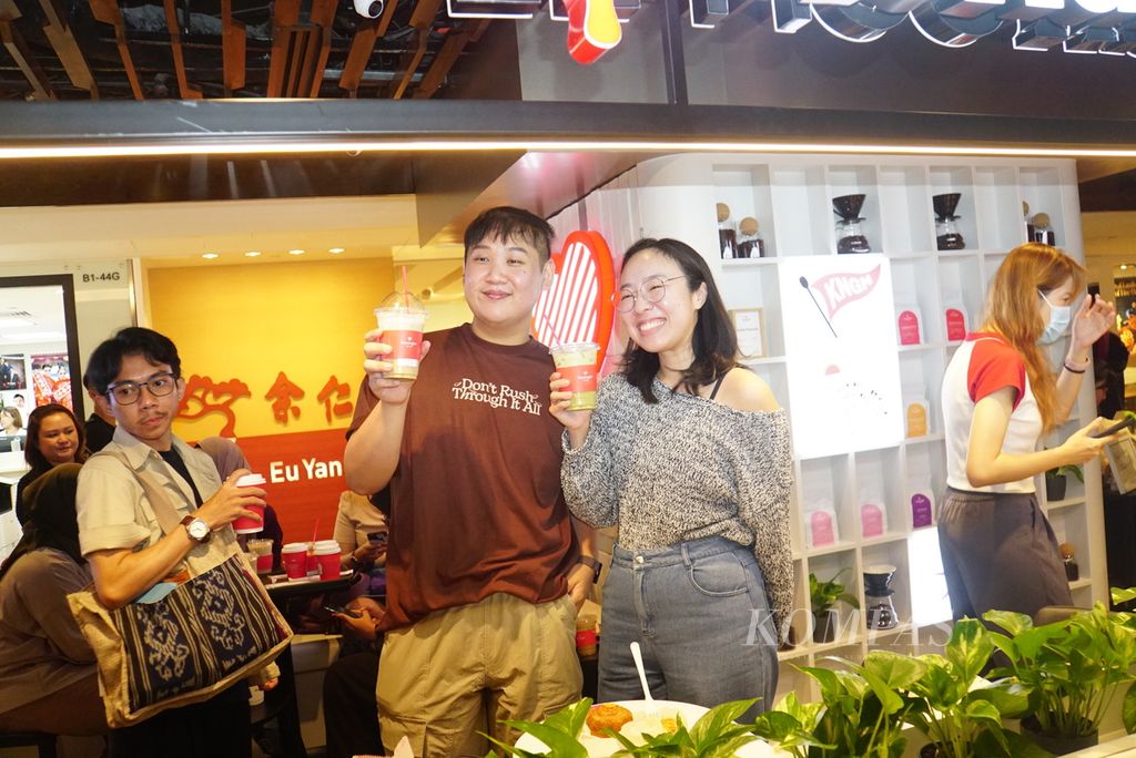 Songyu (30) dan Rachel (24) berfoto dengan minuman mereka di gerai Kenangan Coffee di Singapura, Selasa (26/9/2023).