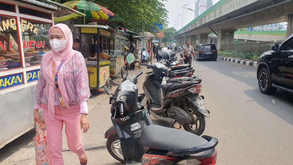 Seorang warga melintas di trotoar di Jalan Kapten Tendean, Mampang Prapatan, Jakarta Selatan pada Selasa (16/5/2023). Dia harus berbagi jalan dengan pedagang dan motor yang parkir di trotoar sehingga mengganggu pedestrian.