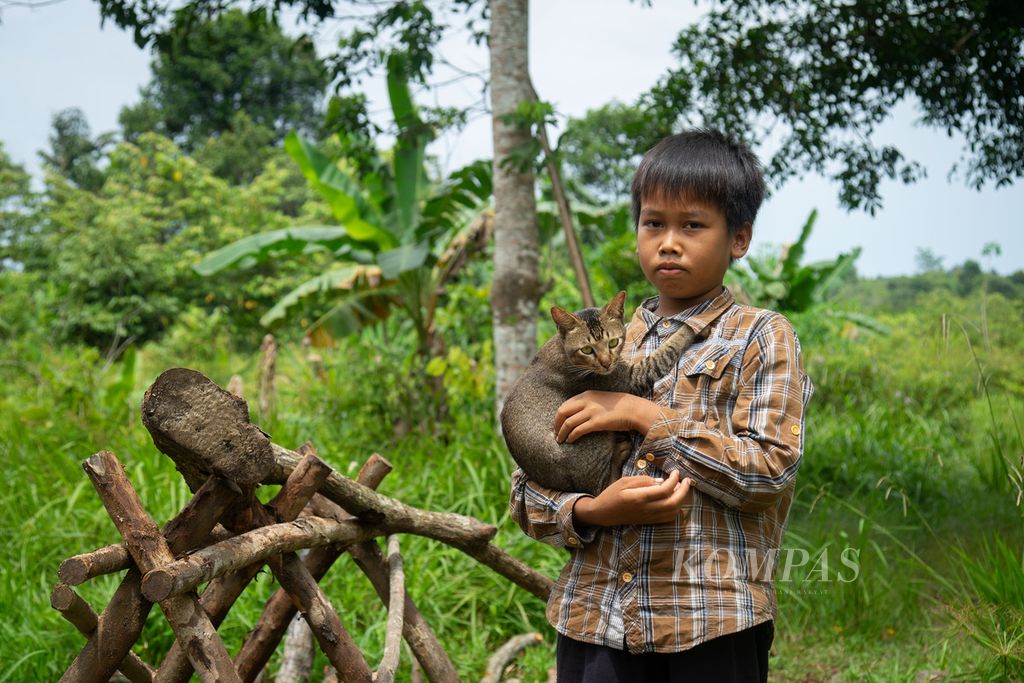 Anak suku Orang Darat, Refi (11), tengah bermain bersama hewan piaraannya di Kampung Sungai Sadap, Kelurahan Rempang Cate, Kecamatan Galang, Kota Batam, Kepulauan Riau, Jumat (5/8/2022).