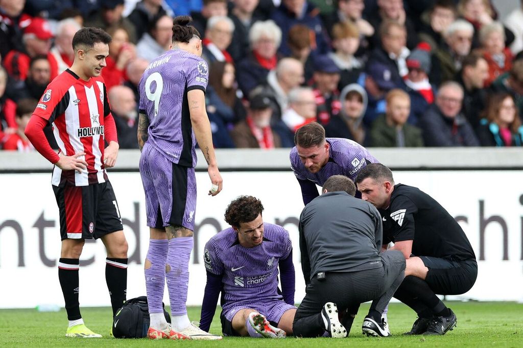 Gelandang Liverpool, Curtis Jones (tengah), mendapat perawatan dari tim medis karena cedera saat laga melawan Brentford, Sabtu (17/2/2024). 
