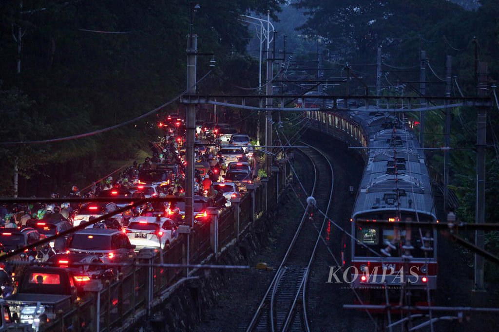 Kereta komuter melintas di samping kendaraan yang terjebak macet dari kawasan Pejompongan menuju Stasiun Kereta Api Palmerah, Jakarta, saat jam pulang kerja, Selasa (11/6/2024). Transportasi publik dapat menjadi salah satu solusi untuk mengurangi kemacetan di Jakarta. Setiap harinya, sekitar 24 juta kendaraan berada di wilayah DKI Jakarta.