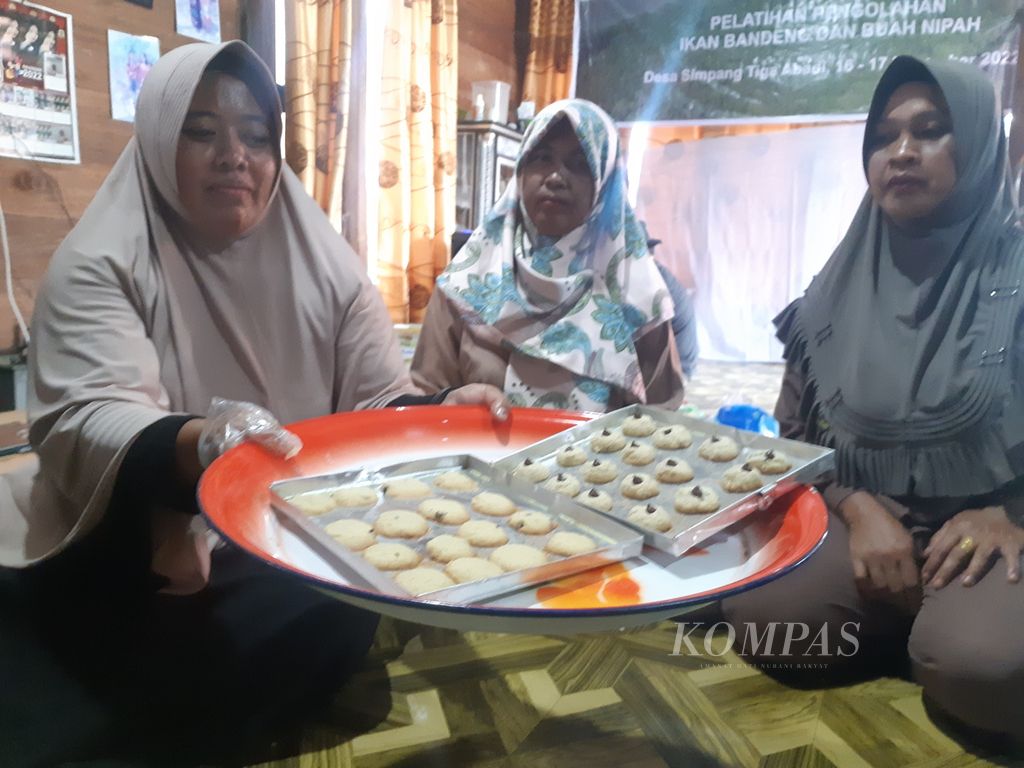 Tiga perempuan di Desa Simpang Tiga Abadi, Kecamatan Tulung Selapan, Kabupaten Ogan Komering Ilir, Sumatera Selatan, sedang membuat kue dari tepung nipah Kamis (17/11/2022). Kue berbahan tepung nipah itu menjadi salah satu produk yang diajarkan kepada para wanita di pesisir untuk meningkatkan kapasitas masing-masing.