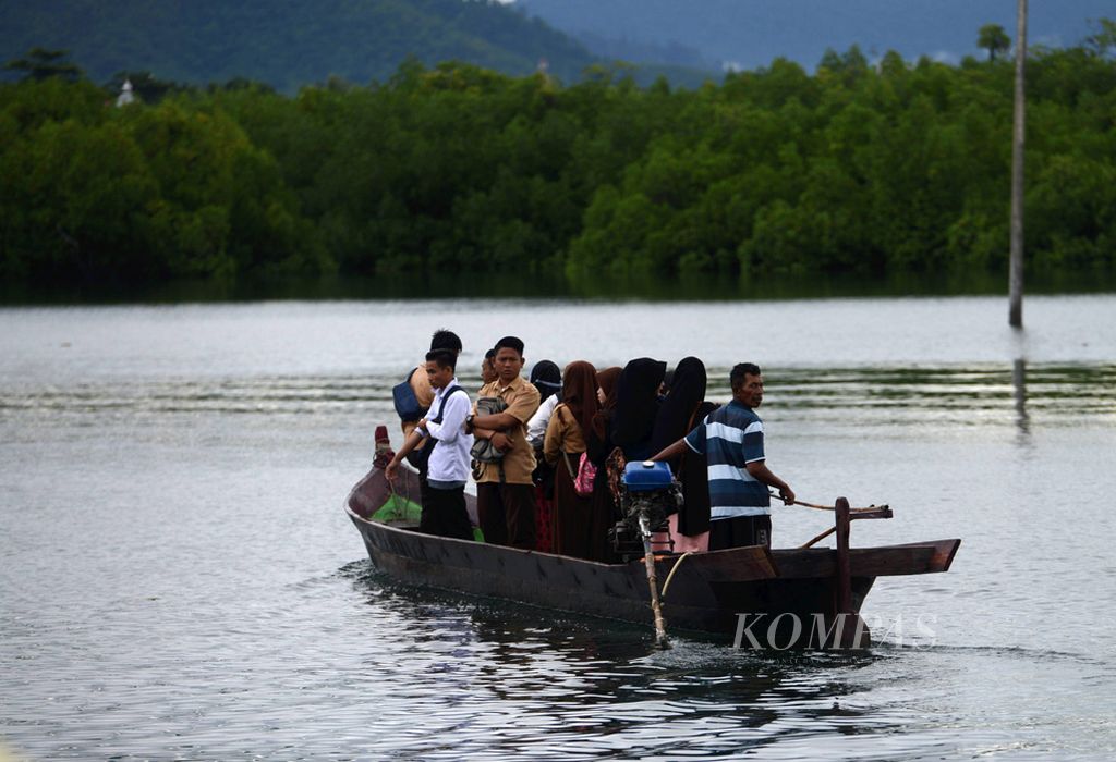 Pelajar naik ojek perahu untuk berangkat sekolah di daratan.