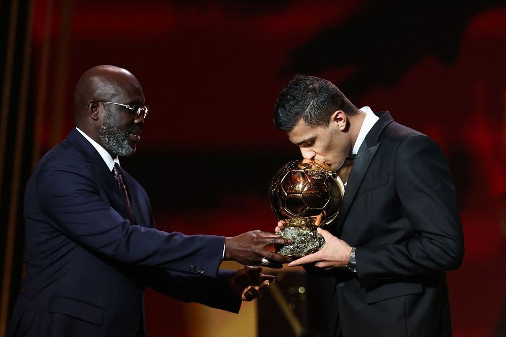 Pemain Manchester City, Rodri (kanan), mencium trofi penghargaan Ballon d'Or 2024 seusai menerimanya dari mantan Presiden dan sekaligus mantan pemain Liberia, George Weah, pada acara di Theatre du Chatelet, Paris, Perancis, Selasa (29/10/2024) dini hari WIB.