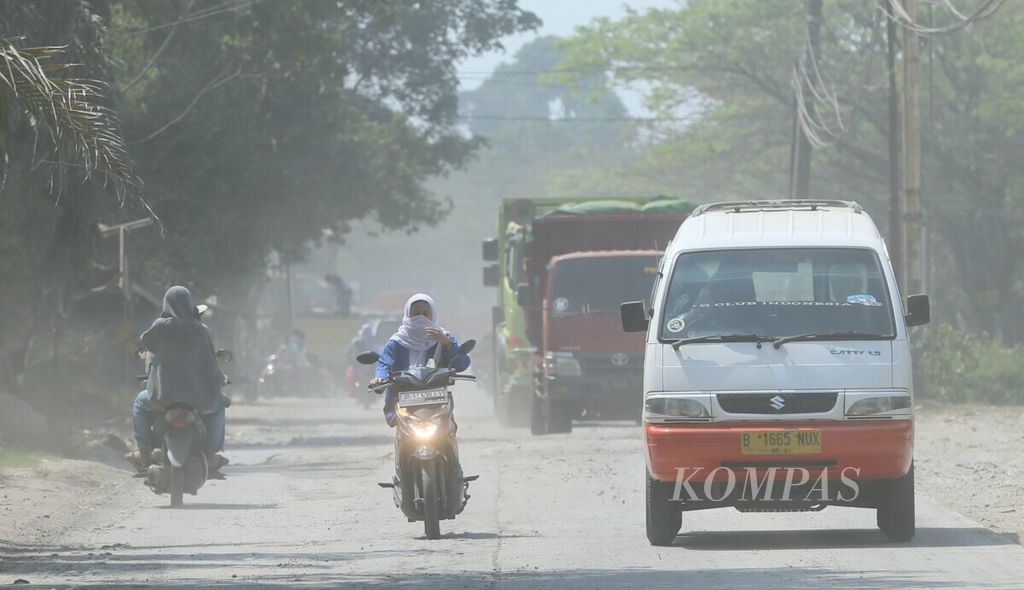 Polusi debu menjadi pemandangan sehari-hari di Jalan Raya Sukamulya, Rumpin, Bogor, Jawa Barat, Kamis (18/7/2019). Polusi debu itu berasal dari ratusan truk pengangkut material yang setiap hari melintasi jalan di kawasan Bogor barat ini. 