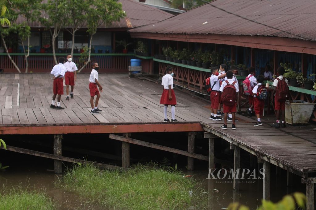 Siswa sekolah dasar di Kota Agats, Asmat, Papua, bermain di halaman sekolah yang berbentuk panggung, sebelum bel pelajaran berbunyi, Selasa (12/10/2021).