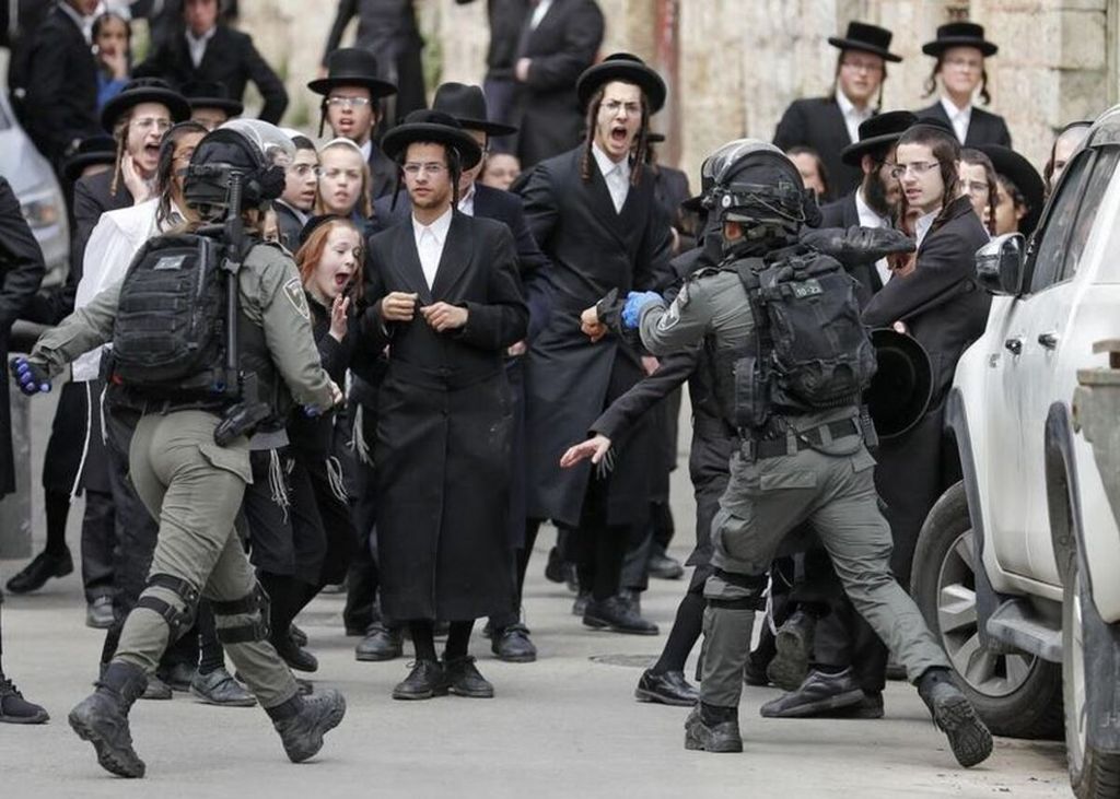 Polisi Israel mengejar warga Mea Shearim, di Jerusalem, Senin (30/3/2020). Mayoritas penduduk di permukiman itu penganut Yahudi ultraortodoks. 