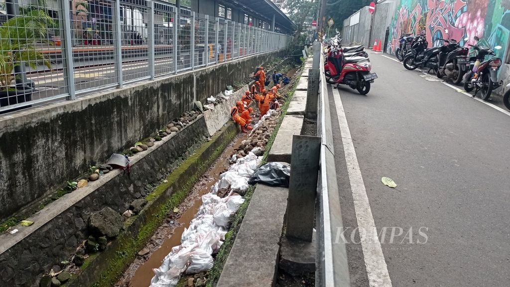 Sebanyak 30 petugas dari Sudin Sumber Daya Air Jakarta Selatan dan pasukan oranye atau PPSU dikerahkan untuk membersihkan longsoran di samping Stasiun Cawang, Jakarta, Kamis (5/1/2022).