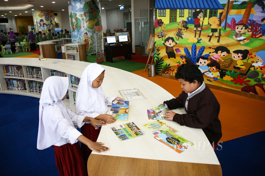 Siswa sekolah dasar menikmati buku bacaannya dalam kunjungan eduktif ke Perpustakaan Nasional Jakarta, Selasa (18/2/2020).