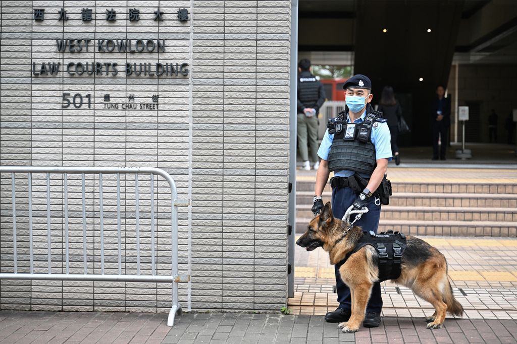 Seorang polisi dan anjing pelacak berjaga di luar gedung Pengadilan West Kowloon tempat taipan media prodemokrasi Hong Kong, Jimmy Lai, diadili, 18 Desember 2023. 