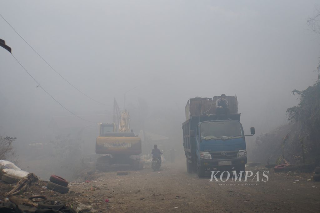 Truk pengangkut sampah melintas menembus kabut asap yang menyelimuti Tempat Pembuangan Akhir (TPA) Sumompo di daerah Tuminting, Manado, Sulawesi Utara, Rabu (4/10/2023).