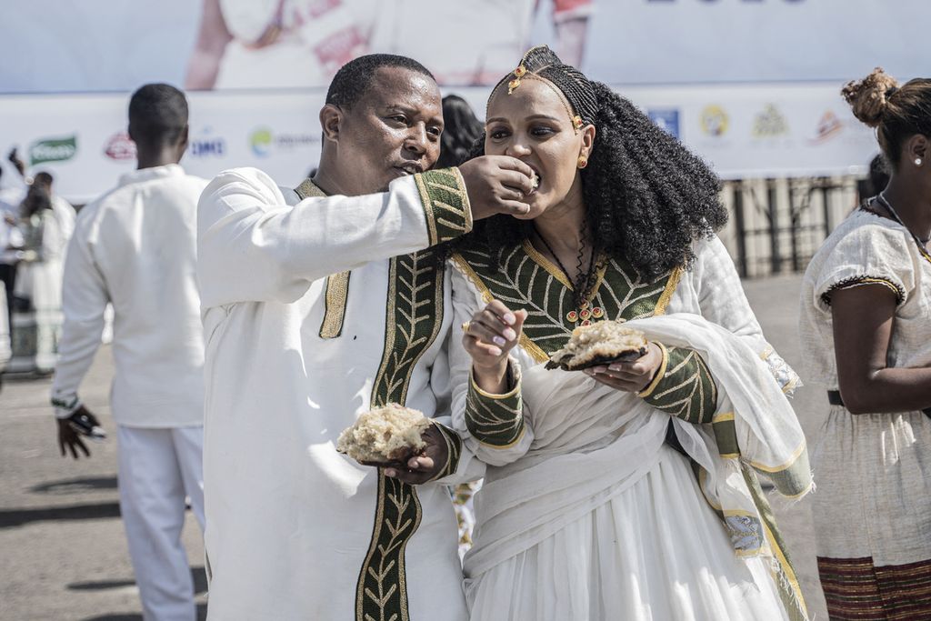 Pasangan yang mengenakan pakaian tradisional saling menyuapkan roti saat pernikahan massal yang disebut Yeshih Gabicha di Addis Ababa, Etiopia, Minggu (14/1/2024).