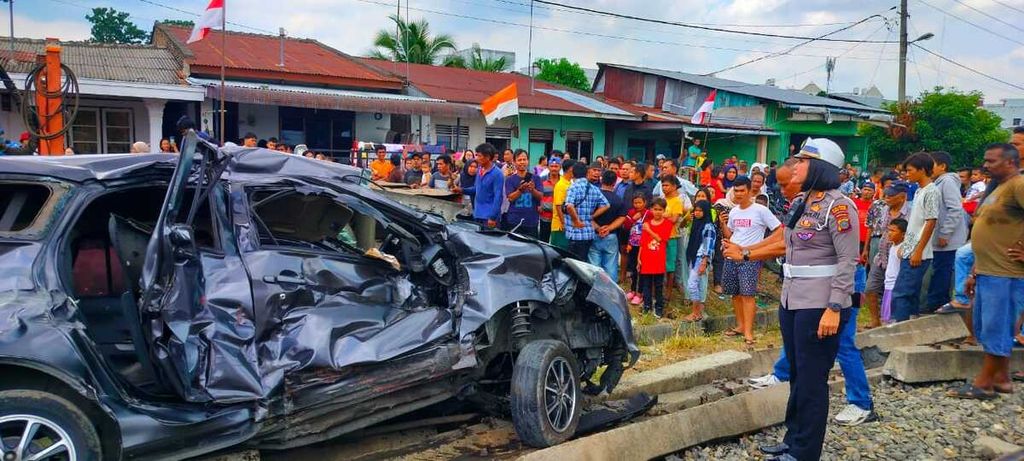 Warga menyaksikan mobil yang tertabrak kereta api di pelintasan sebidang tidak terjaga di Jalan Lama, Kota Tebing Tinggi, Sumatera Utara, Rabu (16/8/2023).