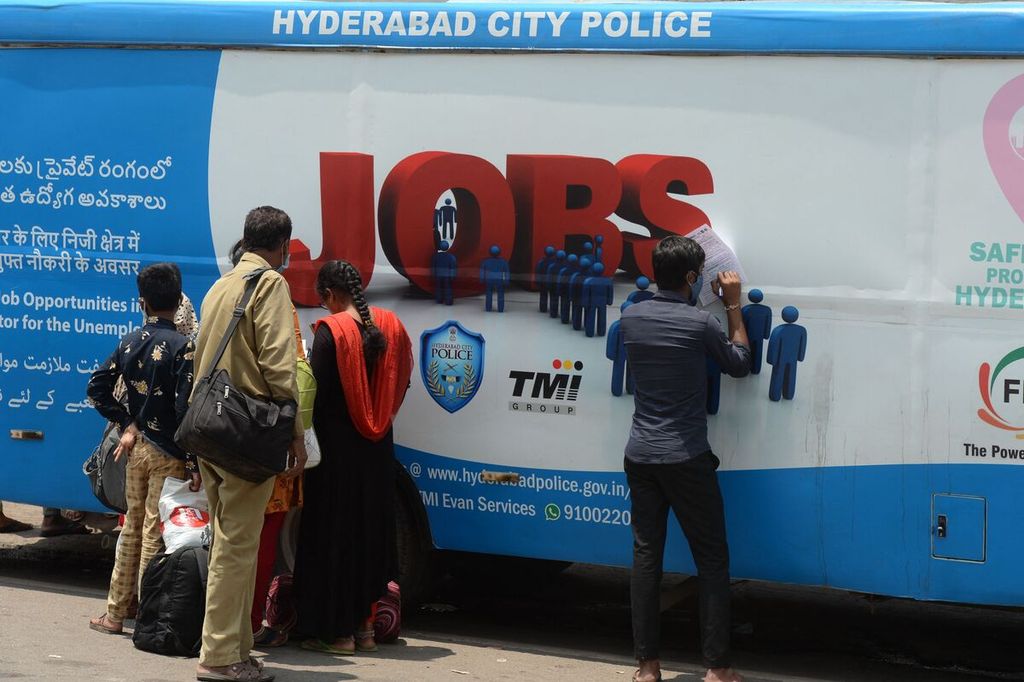 Young unemployed people fill out forms to get jobs in the private sector outside a van that serves as a job field, initiated by the TMI foundation and the Hyderabad city police in Hyderabad, India, on August 15, 2021.