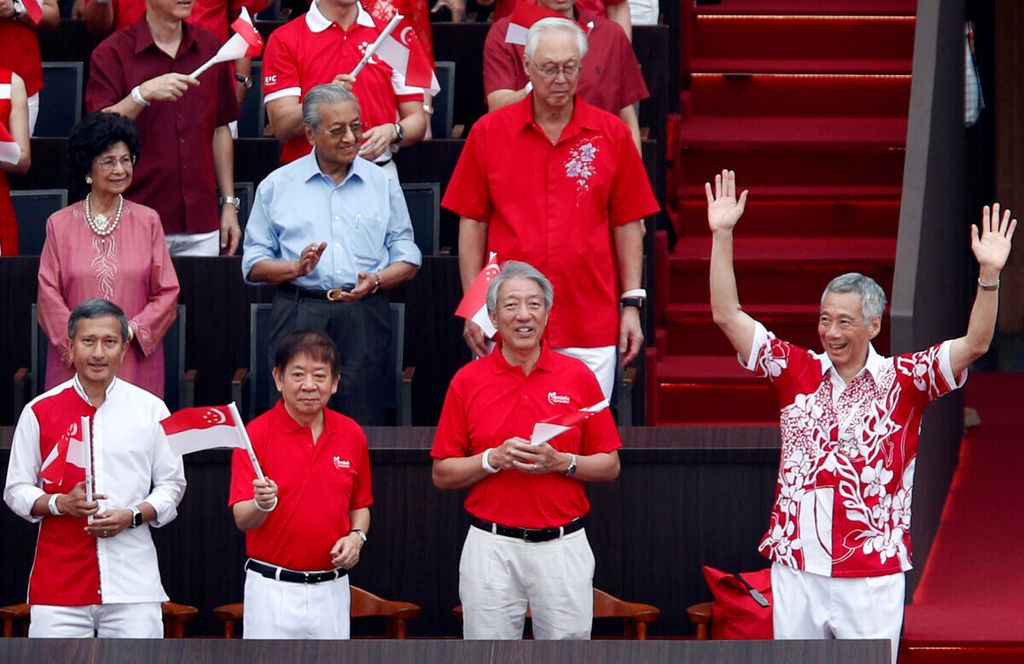 Perdana Menteri Malaysia Mahathir Mohamad dan istrinya, Siti Hasmah, berdiri berdampingan pada Parade Hari Nasional ke-54 di Singapura, 9 Agustus 2019. Hubungan Singapura-Malaysia bolak-balik diwarnai ketegangan karena berbagai isu.