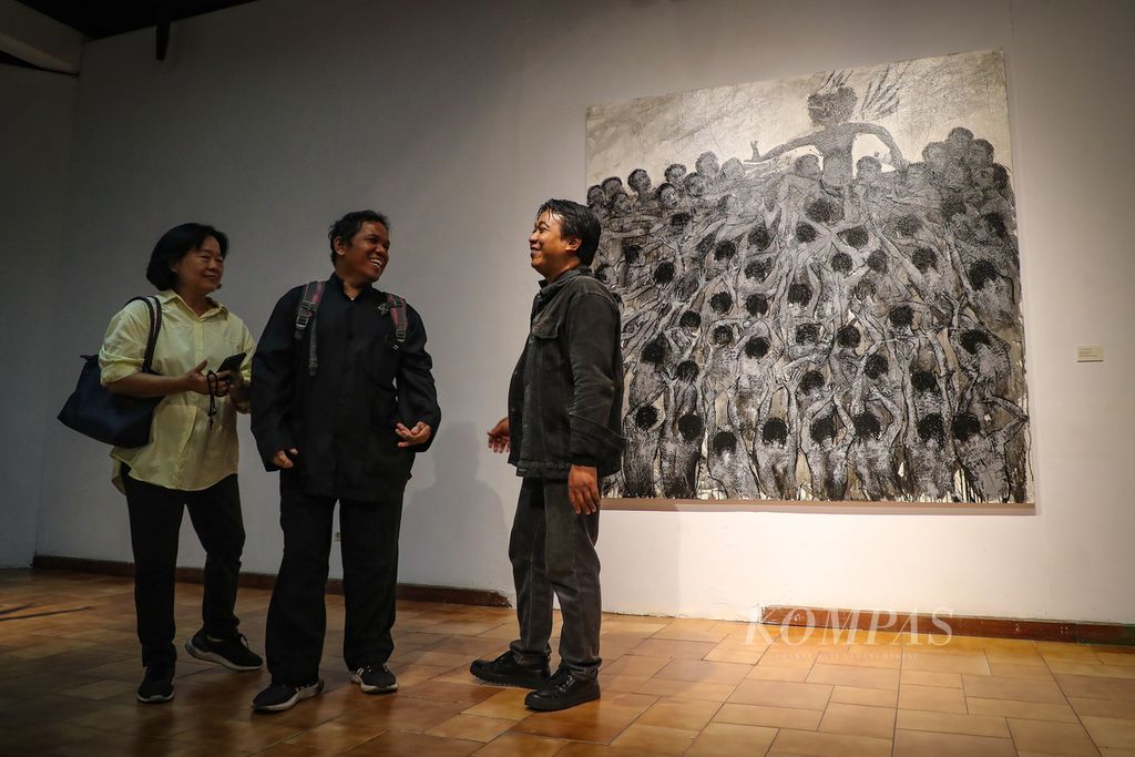Pengunjung berbincang di samping karya Putu Sutawijaya dalam pameran ”Lelampah” di Bentara Budaya Jakarta, Kamis (14/9/2023). Mengangkat tema ”Garuda”, Putu Sutawijaya menampilkan 10 lukisan, 23 lukisan yang diolah dari foto, video dokumentasi riset, serta sejumlah instalasi dan patung. Pameran tersebut berlangsung pada 14-29 September 2023. 