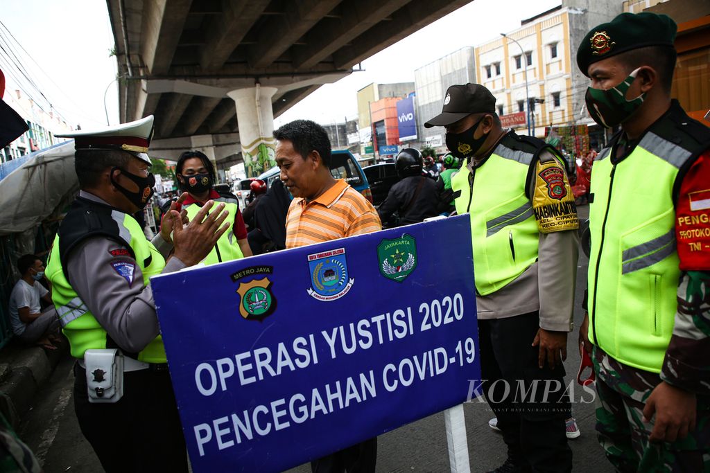 Polisi mengingatkan warga yang terjaring operasi yustisi pencegahan Covid-19 di sekitar Pasar Ciputat, Tangerang Selatan, Banten, Minggu (25/10/2020). Operasi yustisi oleh petugas polisi dan TNI itu juga disertai bagi-bagi masker untuk warga yang tidak mengenakan masker. Tidak ada saksi bagi warga yang terjaring operasi karena tidak mengenakan masker. 