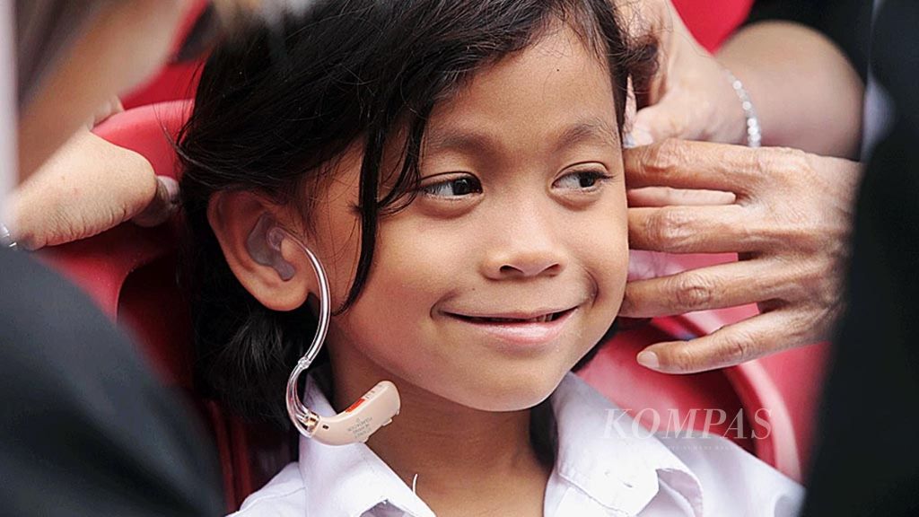 Seorang anak tersenyum saat pertama kali bisa mendengar menggunakan alat bantu dengar yang dibagikan secara gratis untuk orang yang membutuhkan di Kota Malang, Jawa Timur, Kamis (3/8/2017).
