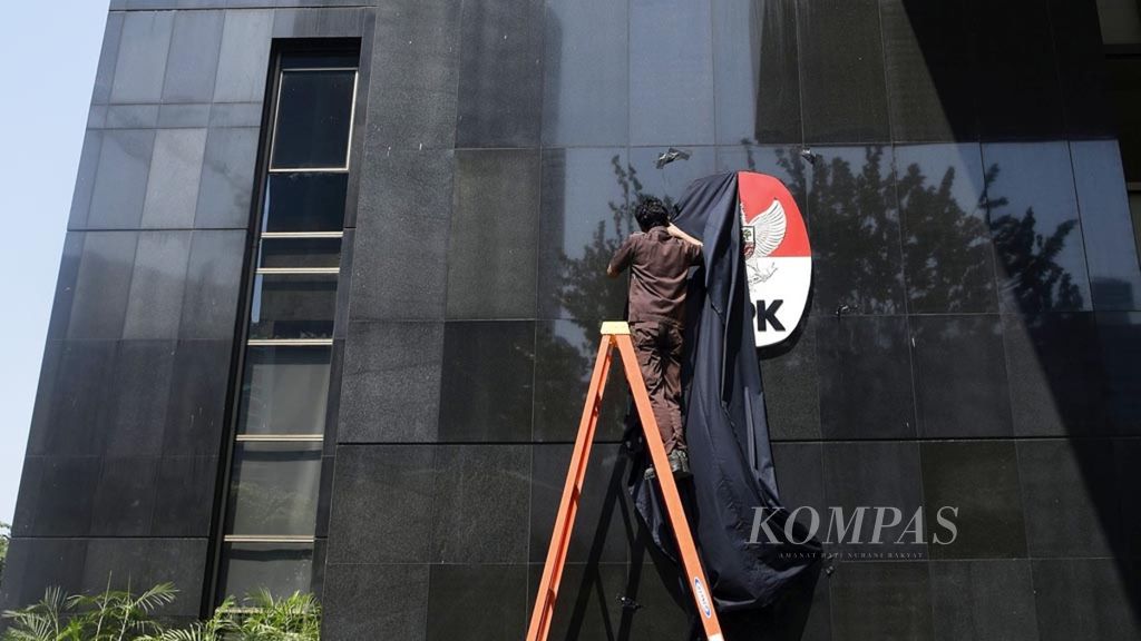 Petugas perawatan gedung membetulkan kain selubung hitam yang menutup logo Komisi Pemberantasan Korupsi (KPK) di Gedung Merah Putih KPK, Jakarta, Selasa (10/9/2019). 
