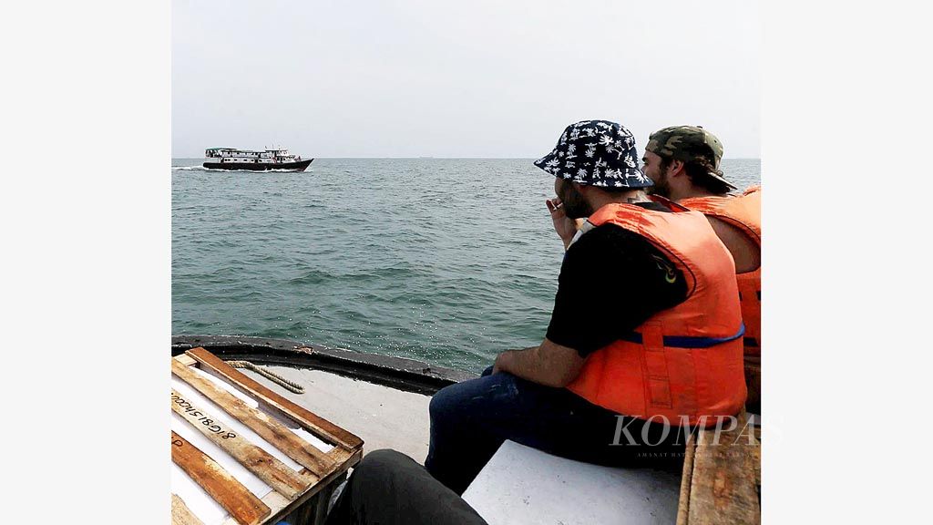 Shando (kanan) turis asal Afrika Selatan dan Javid asal Azerbaijan menikmati perjalanan menuju Pulau Tidung dengan menggunakan kapal tradisional berute Muara Angke-Kepulauan Seribu, Jumat (2/2.